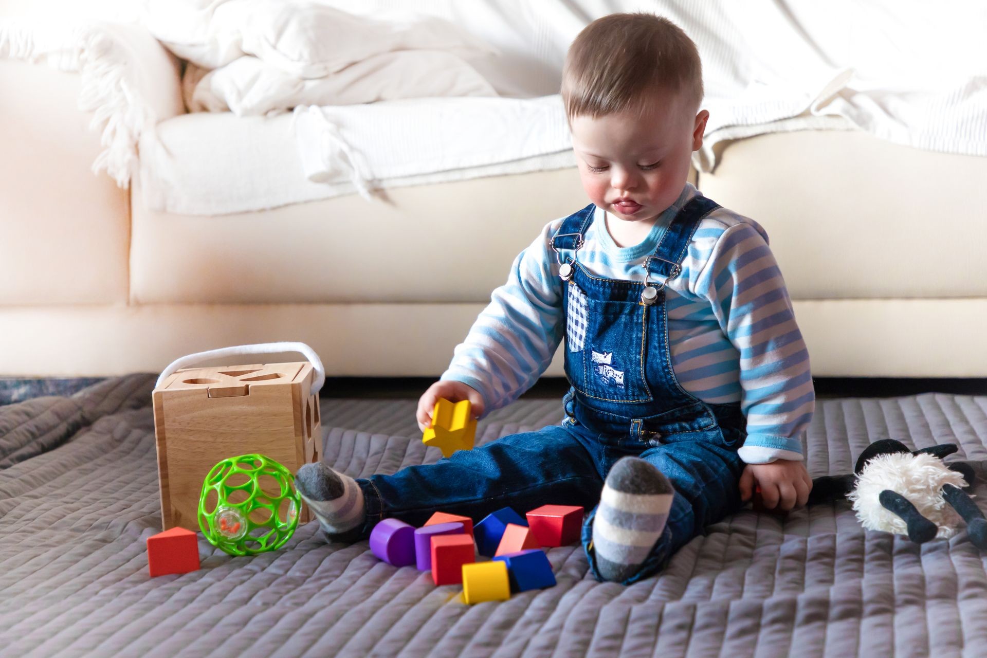 Portrait of cute baby boy with Down syndrome playing in home living room Portrait of cute baby boy with Down syndrome playing in home living room