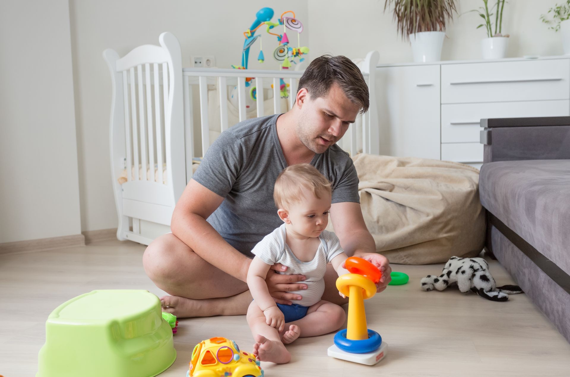Father sitting on floor with his baby and playing with toys Father sitting on floor with his baby and playing with toys